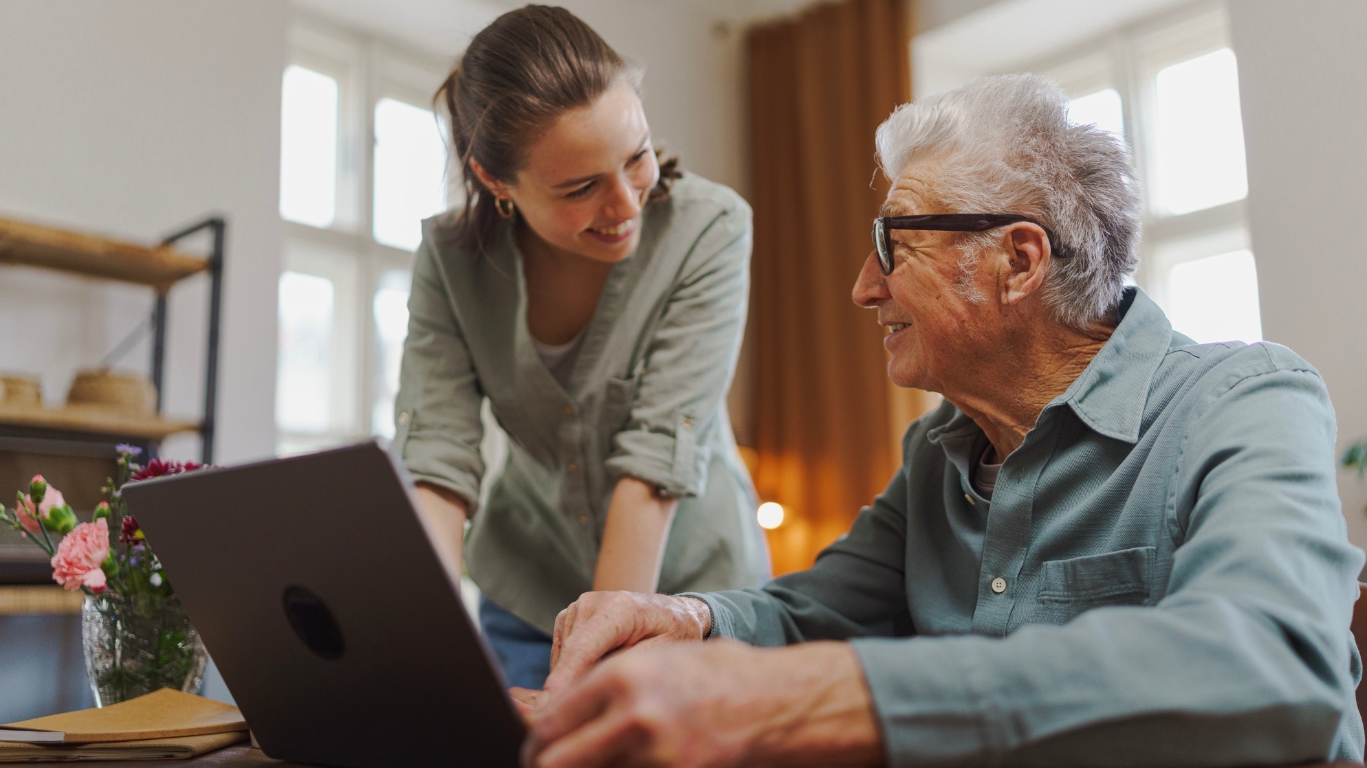 Granddaughter showing something to her grandfather on laptop